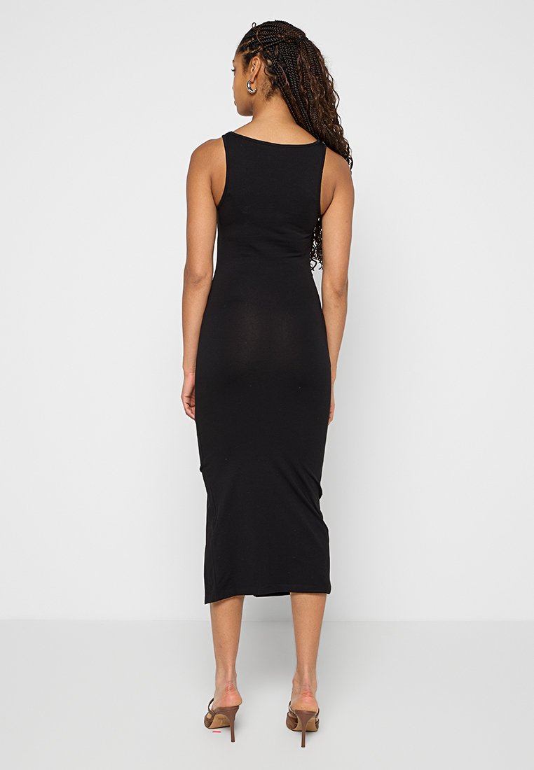 Schwarzes ärmelloses Midikleid mit tailliertem Schnitt, glatter Textur und knielangem Saum, getragen mit offenen High Heels.
