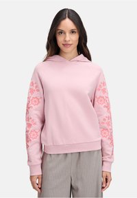 Felpa rosa chiaro con cappuccio, caratterizzata da ricami floreali in rosa scuro sulle maniche e una vestibilità comoda. Tessuto dalla consistenza liscia.