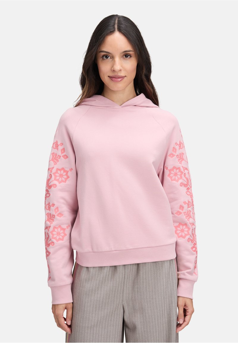 Felpa rosa chiaro con cappuccio, caratterizzata da ricami floreali in rosa scuro sulle maniche e una vestibilità comoda. Tessuto dalla consistenza liscia.