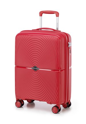 Valise rigide rouge avec texture ondulée, fermeture éclair, poignée extensible et quatre roues pour la mobilité. Logo de la marque affiché de manière proéminente.