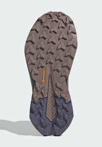 Semelle extérieure en caoutchouc brun avec un motif de crampons profond et multidirectionnel et une section centrale lisse. Présente un logo "Continental" jaune.