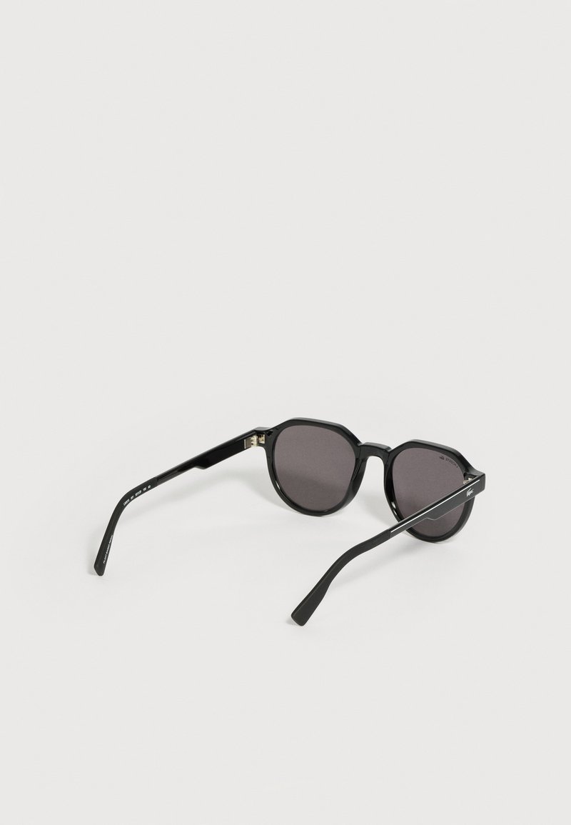 Black rectangular sunglasses with dark lenses and slim arms resting open on a white surface.