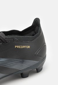 Stivale da calcio nero in materiale sintetico testurizzato, con design a taglio basso, marchio dorato "PREDATOR" e dettagli a fantasia.