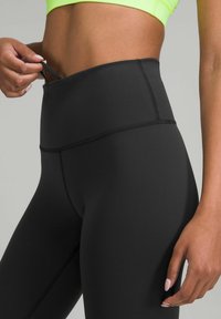 Zwarte hoge taille leggings van rekbare stof; met een gladde textuur, naaddetail en een zak voor kleine items.