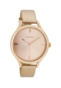 Montre ronde avec un boîtier en métal doré rose, un cadran métallique rose et un bracelet en cuir beige doux. Présente des marqueurs d'heure minimalistes.