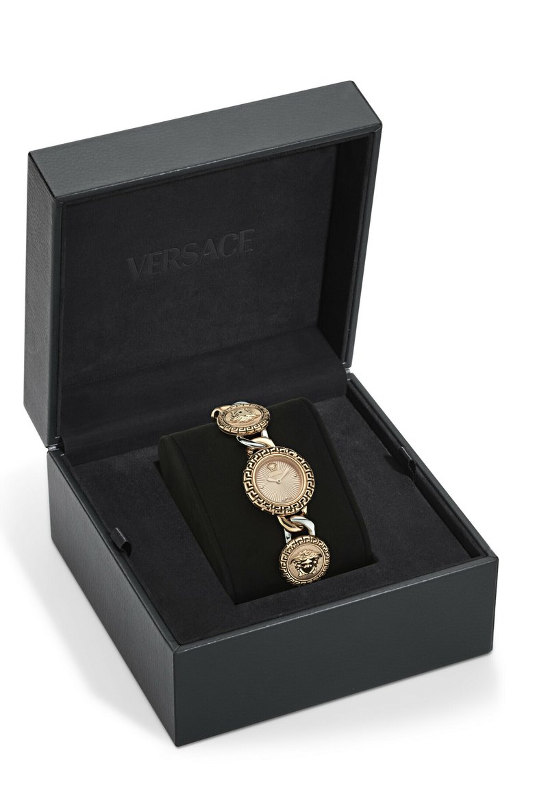 Montre bracelet dorée avec des motifs de clé grecque et de médaillon, présentée dans une boîte noire avec un intérieur noir doux, arborant un logo Versace.