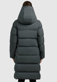 Mørkegrå lang dunjakke med hætte. Har et kviltet design, isolerende polstring og en slank silhuet. Lynlåslommer i siden er synlige.