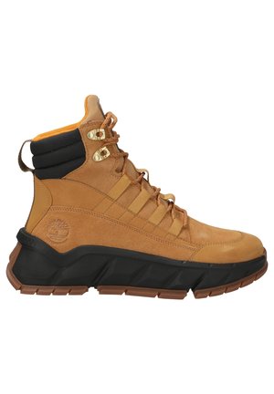Botte de randonnée beige et noire avec cheville rembourrée, œillets métalliques et semelle épaisse avec profondes rainures, vue de côté.