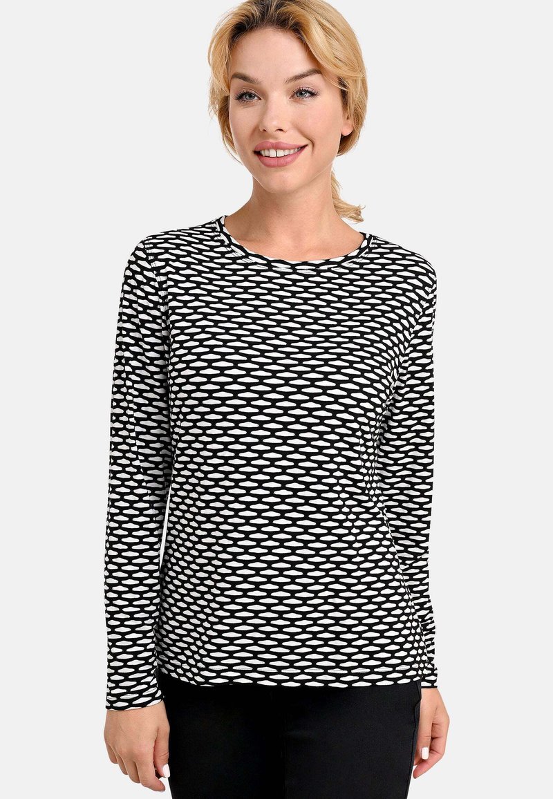 Long-sleeve shirt in a black-and-white zigzag pattern, made of soft fabric with a rounded neckline and fitted design.