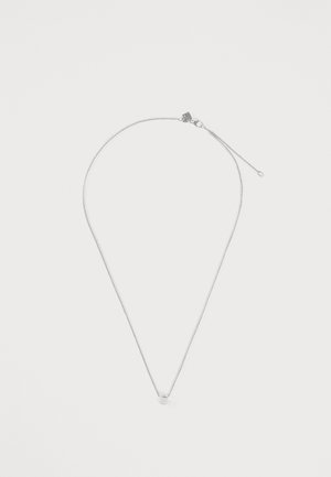 Delicado collar de cadena de plata con un pequeño colgante circular y cierre de langosta sobre un fondo blanco liso.