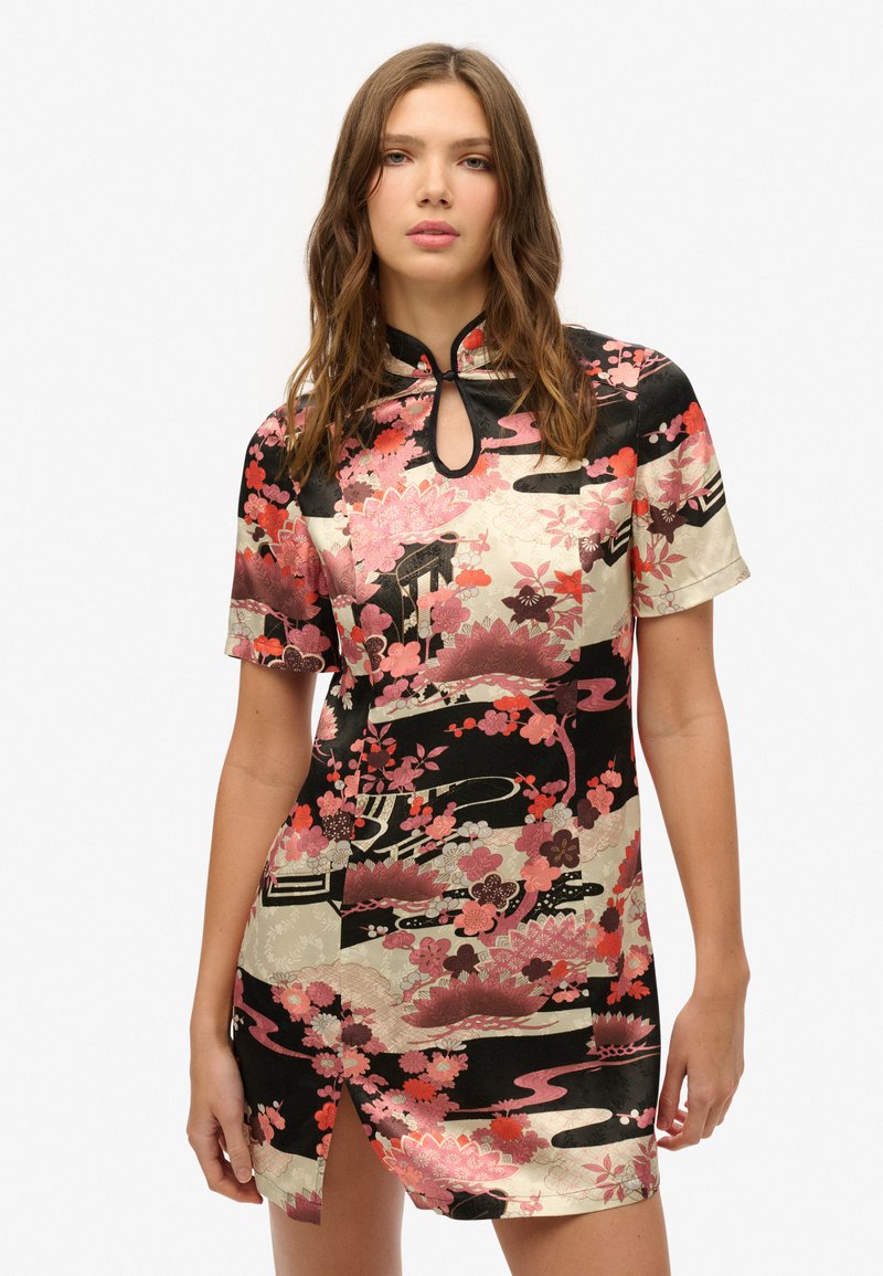 Vestido mini con estampado floral, de cuello alto y detalle de ojal. Presenta colores rosa, rojo y negro en una tela similar a la seda.