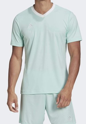 Man draagt licht turquoise Adidas V-hals shirt met korte mouwen en bijpassende korte broek, toont bovenlichaam en armen.