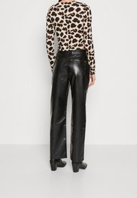 Svarta läderbyxor med vida ben och en slät yta, som har två bakfickor och hög midja. Kombineras med en långärmad topp i leopardmönster.