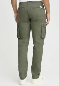 Groene cargobroek met een slim fit, voorzien van dubbele zijzakken, achterzakken en een zachte textuur. G gedragen met witte sneakers.