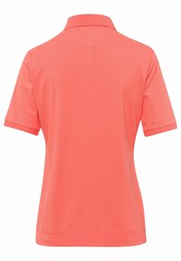 Korálová polo tričko s límečkem a krátkými rukávy. Hladký povrch, žádné viditelné vzory nebo kovové detaily. Zadní pohled ukazuje konturovaný šev.