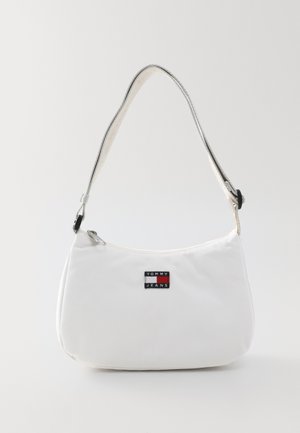 White fabric shoulder bag with a rounded shape. Features a silver strap and a black logo patch with red and blue accents. Zipper closure.