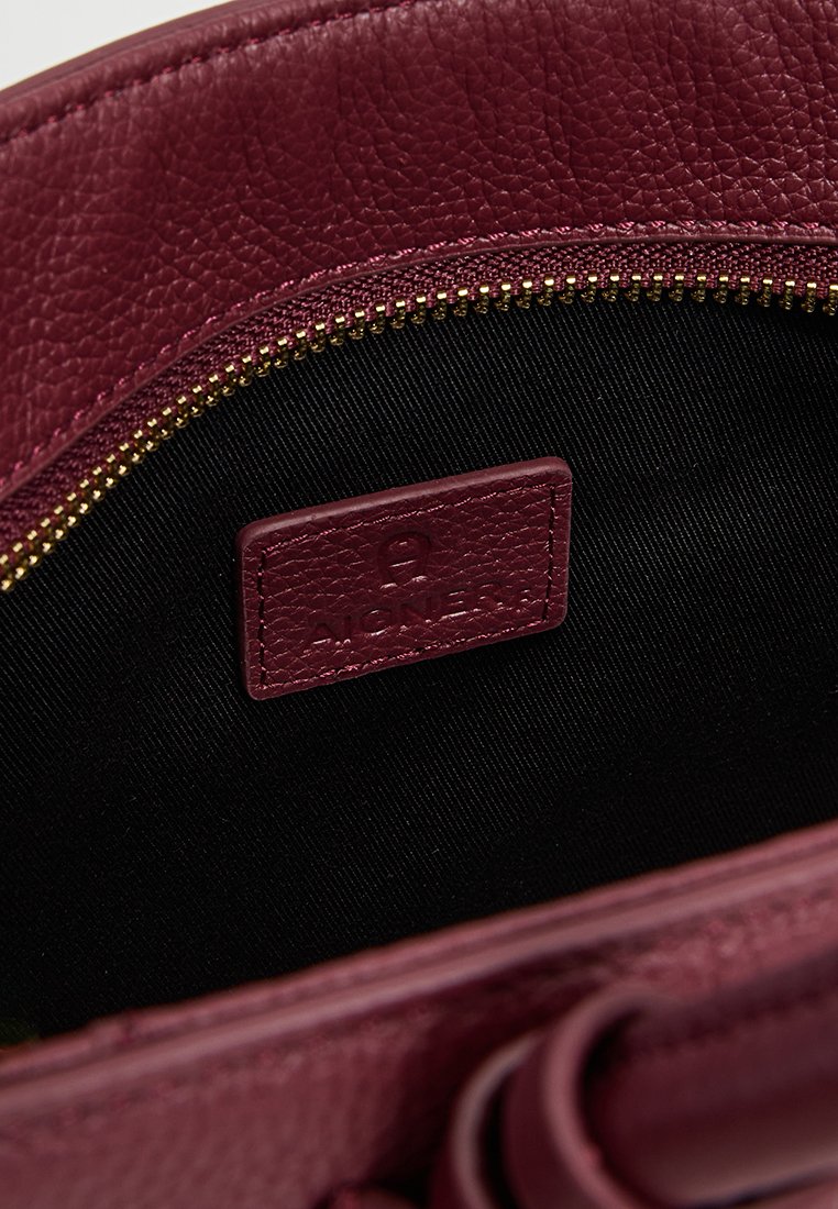 Innenansicht einer burgunderfarbenen Ledertasche mit goldenem Reißverschluss und schwarzem Stofffutter; verfügt über ein markiertes Lederetikett mit der Prägung "AIGNER."