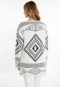 Langärmliger Pullover in Creme mit navyblauen geometrischen Mustern; verfügt über eine lockere Passform, einen runden Ausschnitt und ein strukturiertes Strickgewebe.