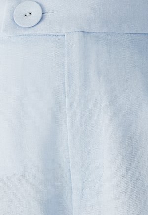 Jasnoniebieska tkanina o teksturowym wykończeniu, z dużym guzikiem w pasie i boczną kieszenią. Proste, czyste linie.