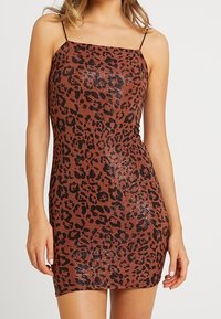 Robe mini imprimée léopard dans une palette de couleurs marron et noire, avec de fines bretelles spaghetti et une finition texturée pailletée.