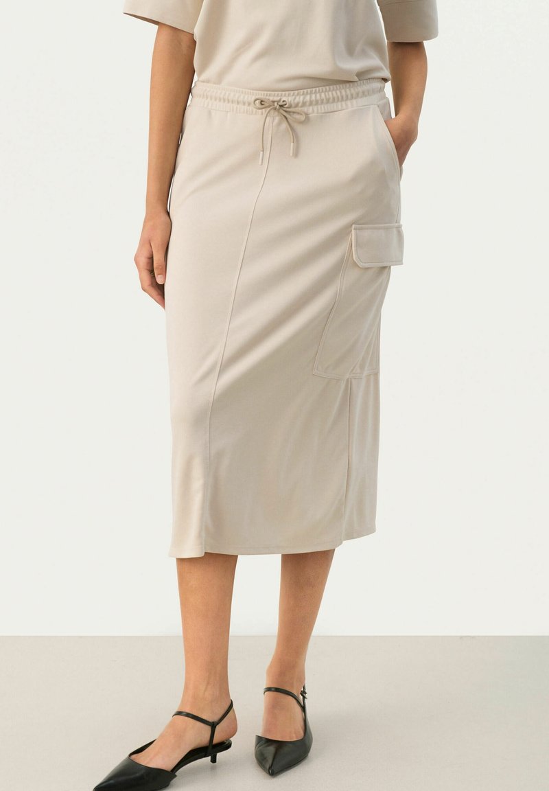 Jupe beige mi-longue en tissu doux, dotée d'une taille élastique avec cordon et d'une poche latérale. Texture lisse.