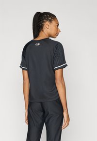 Black athletic shirt with short sleeves, made of moisture-wicking fabric. Features a round neck and white accent stripes on the sleeves.