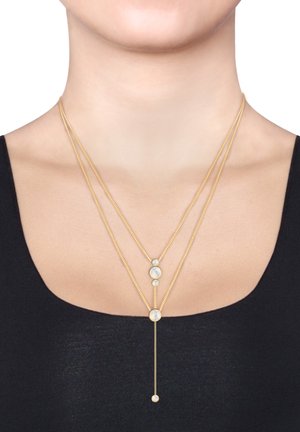 Collier multi-couches en or avec des perles opalescentes circulaires, présentant un design lariat et une texture de chaîne fine, porté sur un haut noir.