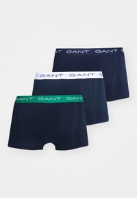 Tre par med boxere i mørk marineblå, med hvit elastikk med logo, og én med grønn elastikk. Glatt stoff, standard passform.