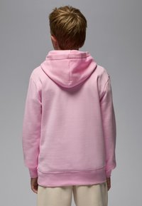 Rosa hettegenser med romslig hette, ribbestrikkede mansjetter og myk tekstur, med et avslappet snitt og minimal detaljering. Bakside vist.