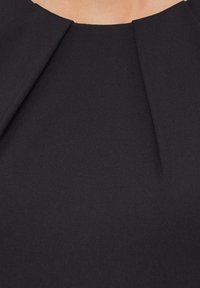 T-shirt noir avec un col rond présentant de légères plissures. Le tissu a une texture lisse, offrant une silhouette ajustée. Pas de détails supplémentaires.