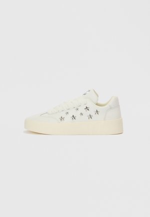 Valge toss, ülaosa sileda nahaga. Lisanduvad hõbedased tähekujulised kaunistused ja paks, tekstuuriga tallaga. Paeltega kinnitus.