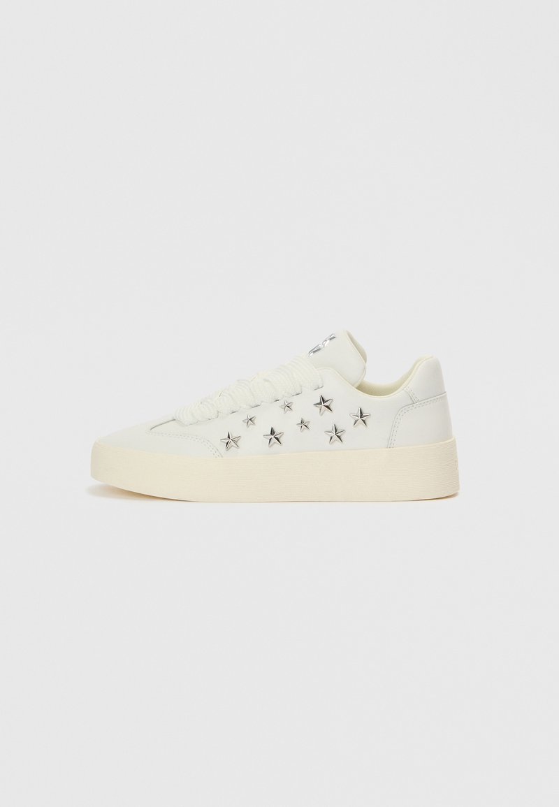 Λευκό αθλητικό παπούτσι με λείο δέρμα στο επάνω μέρος. Διαθέτει ασημένιες διακοσμήσεις σε σχήμα αστέρα και παχύ, υφασμένο πέλμα. Κλείσιμο με κορδόνια.