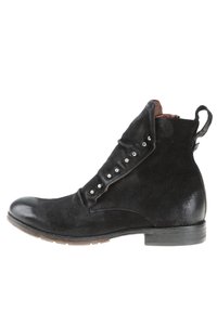 Bottine en cuir noir avec une tige en daim, un rabat plié orné de clous argentés et un talon court. Surfaces lisses et texturées.