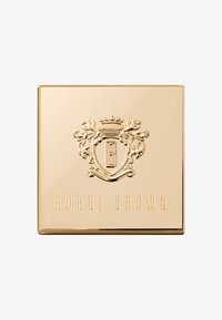 Bobbi Brown kompakt med en reflekterende gullfarget utside, preget våpenskjold med en stor 'B', og hevet tekst som leser "BOBBI BROWN."
