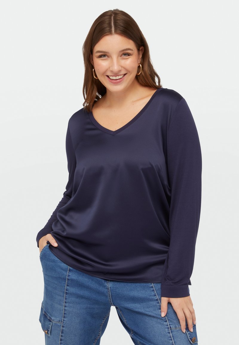 Marineblauw, langesleeve V-hals top van een gladde, glanzende stof, met een comfortabele pasvorm en subtiele draping. Geen patronen of accenten zichtbaar.