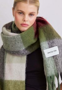 Wollen sjaal in een groen, grijs en bordeaux geruit design, met franjes aan de randen en een geweven label met de tekst "ARCTIC FOX." Zachte, gestructureerde afwerking.