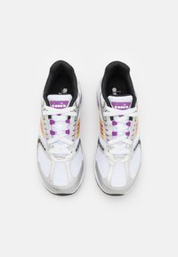 Scarpe atletiche bianche con materiale in rete, dettagli argentati, decorazioni laterali viola e arancioni, e interno nero. Presentano lacci bianchi e logo.