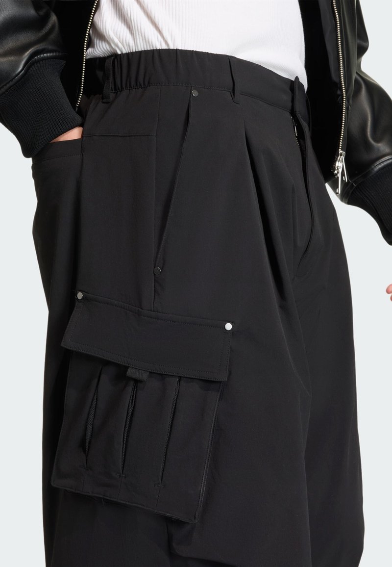 Svarta cargobyxor med elastisk midjeresål, veck och en stor sidficka med tryckknappar. Mjukt, lätt tyg.