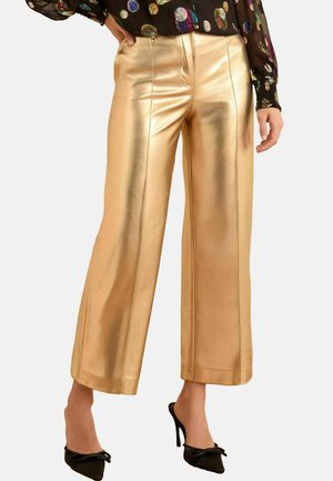 Metallisch goldene weite Hosen mit glatter Textur, ausgestattet mit maßgeschneiderten Nähten und einer mittelhohen Taille. Kombiniert mit schwarzen High Heels.