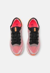 Chaussures de sport légères avec une tige en mesh rose et grise, lacets noirs et un talon orange. Elles comportent une semelle intérieure rembourrée et une semelle flexible.