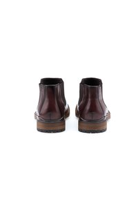 Botas de cuero marrón hasta el tobillo con paneles laterales elásticos, puntera redondeada y tacón dividido. Textura suave y detalles de costura mínimos.