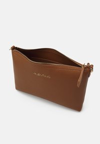 Hnědá kožená clutch taška s texturou a zlatým zipem a brandingem. Design je obdélníkový s horním zipovým uzávěrem a úzkým koženým poutkem.