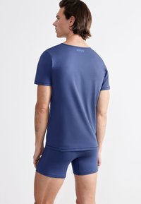 Navy blue athletic short-sleeve top and matching shorts made from smooth, stretch fabric; features a rounded neckline and subtle logo at the back.