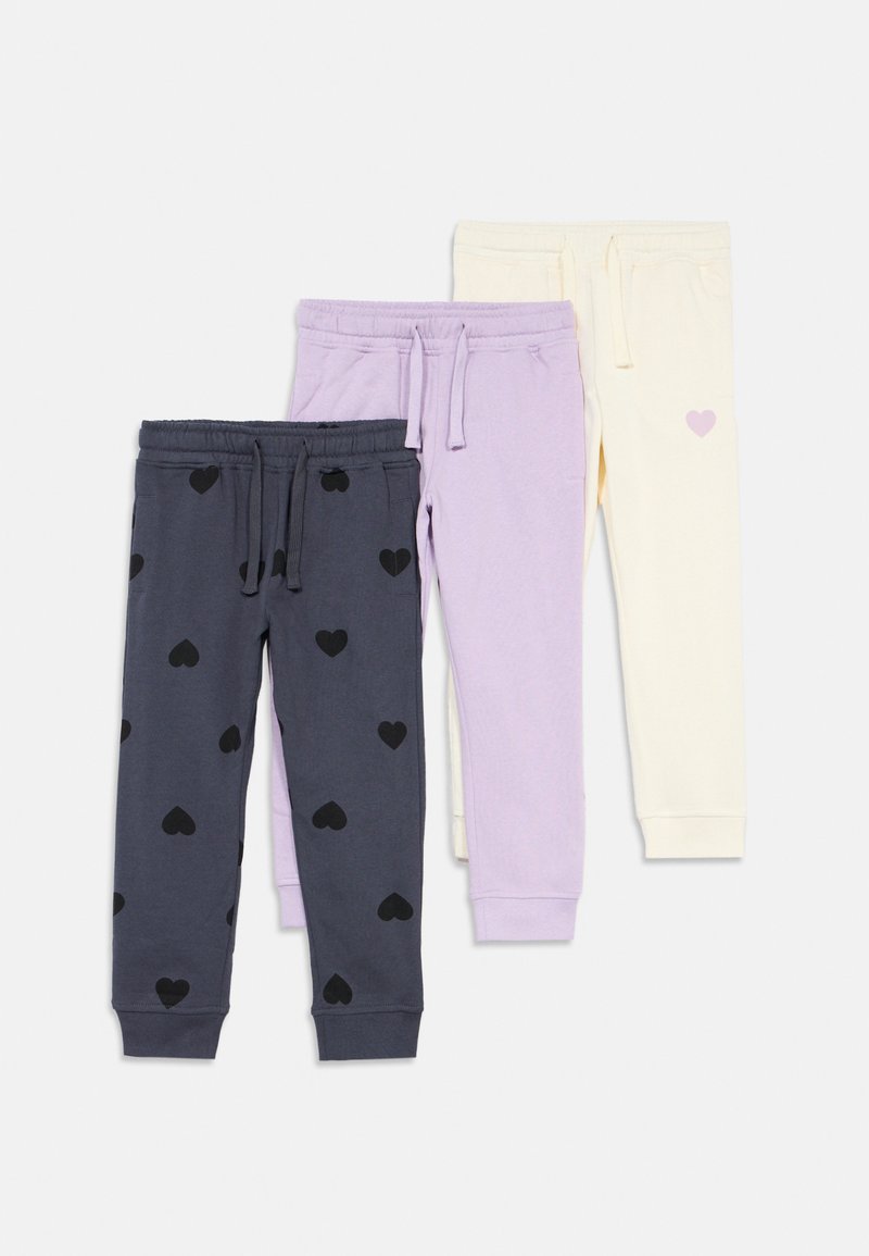 Drei Paar Kinder-Jogginghosen in Schwarz mit Herzmustern, einfarbig Lavendel und einfarbig Creme mit einem kleinen lila Herzen, flach ausgelegt.
