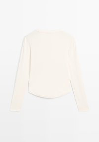 Langarm, off-white dames top met een ronde halslijn en afgeronde zoom, weergegeven vanaf de achterkant op een witte achtergrond.