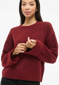 Burgundiapunane kootud kampsun kaelusega, soonikkoes mansettide ja äärega. Pehme tekstuur, lõdva istuvusega ja laiad varrukad.