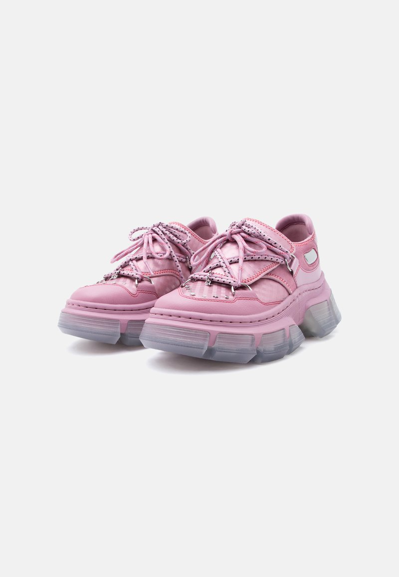 Klobige pinke Sneakers mit dicken, durchscheinenden Sohlen, mehreren Schnürsenkeln und sichtbaren Nähten, nebeneinander auf weißem Hintergrund platziert.