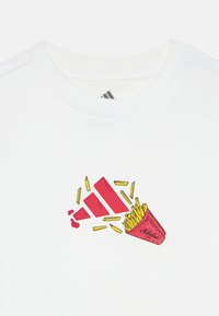 Camiseta de algodão branca com estampa vermelha e amarela de batatas fritas e logótipo da Adidas. Decote redondo com acabamento canelado, textura suave.