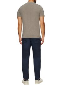 Grijze T-shirt met korte mouwen en een subtiele textuurafwerking, gecombineerd met donkerblauwe rechte jeans en witte sneakers.