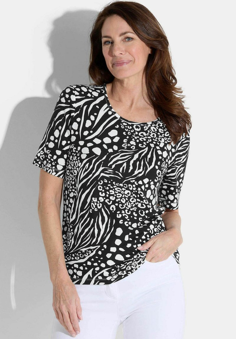 Zwart-wit gestreept T-shirt met dierenprintmotieven, korte mouwen en een ronde halslijn, gecombineerd met witte broeken. Gladde stoftextuur.